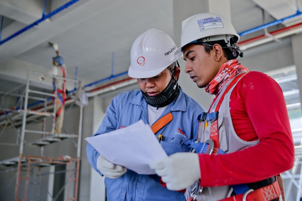 Construction workers with hard hats discussing notice of intent to lien paperwork