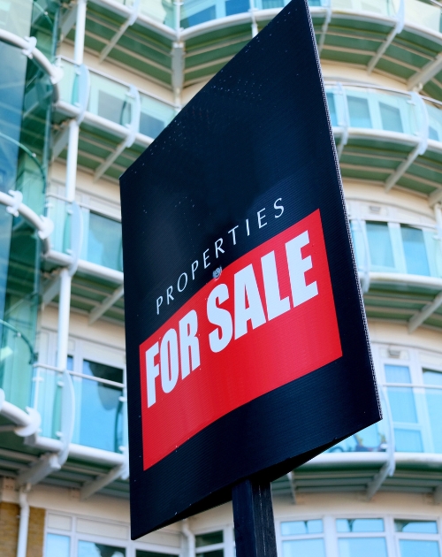A Property for Sale sign with a building apartment behind